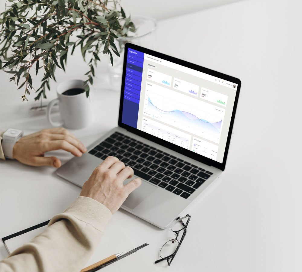 Unas manos sobre el teclado de un ordenador portátil que muestra imágenes de la plataforma web de HygieneIN